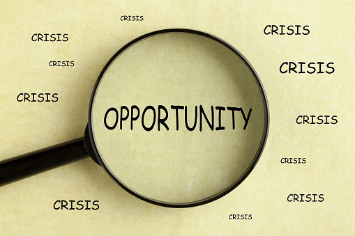 Magnifying glass over the word opportunityon and crisis concept background