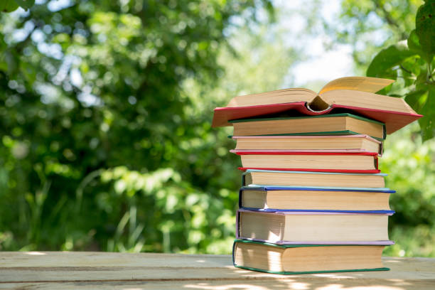 libro abierto sobre una mesa de madera en un jardín. día soleado de verano, leyendo en un concepto de vacaciones - open book teaching table fotografías e imágenes de stock