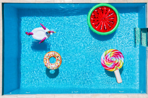 Aerial view of many multi colored inflatables on a swimming pool Aerial view of many multi colored inflatables on a square swimming pool with crystal clean, blue water swimming float stock pictures, royalty-free photos & images