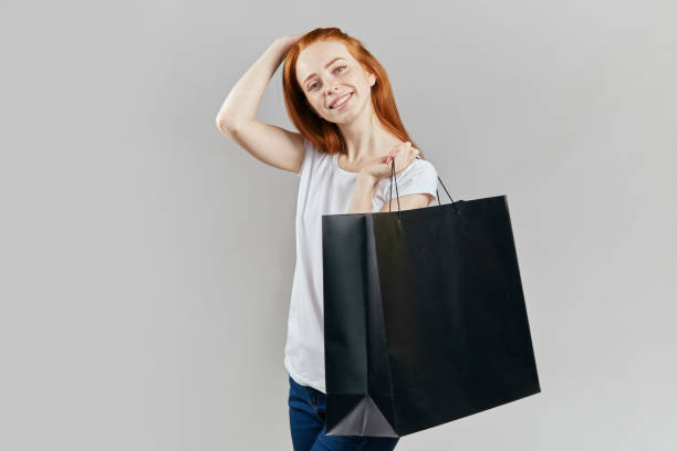 istock charming red-haired girl with a purchase looking at the camera 1241495037