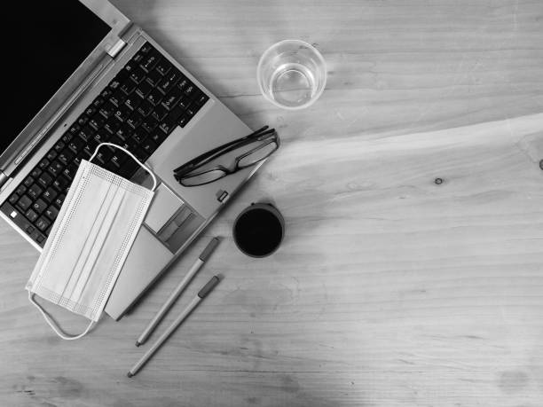 istock workplace at home for remote work - smart working  in new normal everyday with silver laptop on wood table and 3 ply surgical face mask - solution against spread of coronavirus for employees in confinement  during COVID-19 outbreak. 1241495043