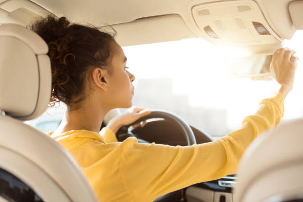 istock African Woman Adjusting Mirrors Checking Auto During Test Drive, Back-View 1241496175