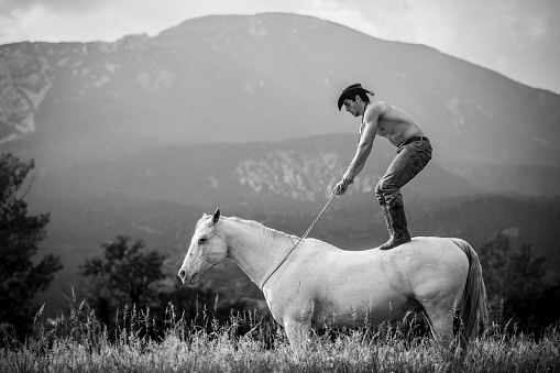 Black and White Image of Young Adult Man Standing Up on a Horse.