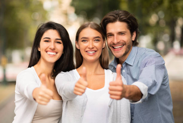 istock Three Happy Friends Gesturing Thumbs Up Standing Outdoor 1241503410