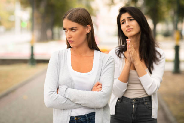 Girl Begging Offended Female Friend To Remain Friends Standing Outdoors Girl Begging Offended Female Friend To Remain Friends After Quarrel Standing Outdoors. Selective Focus pleading stock pictures, royalty-free photos & images