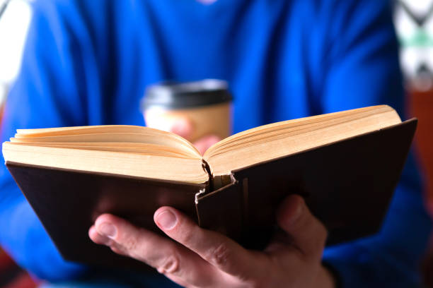 istock Man read a book and holds a coffee cup 1241543863