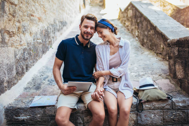 istock Romantic tourist couple sitting on stairs using digital tablet. 1241546609