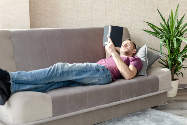 istock young man resting in a bright room lying on a sofa and reading a book 1241557206