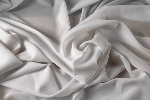 White fine chiffon fabric with a woven texture. Gathered in a spiral and crushed textiles. Silky light stock photo
