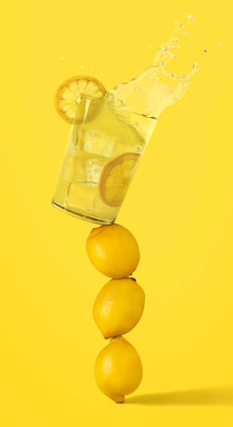 Lemonade glass is on top of several lemons in balance and is about to fall Glass of refreshing lemonade is on top of several lemons in balance and is about to fall. Summer time. lemon soda photos stock pictures, royalty-free photos & images