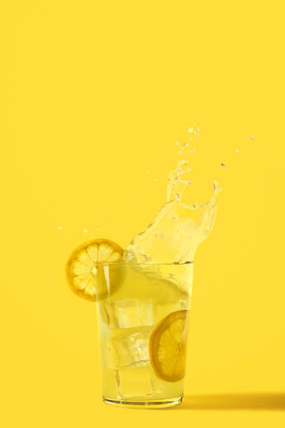 Glass of refreshing lemonade where ice falls and makes a splash stock photo