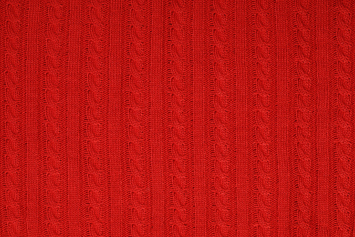 Real red knitted fabric with cable pattern textured background