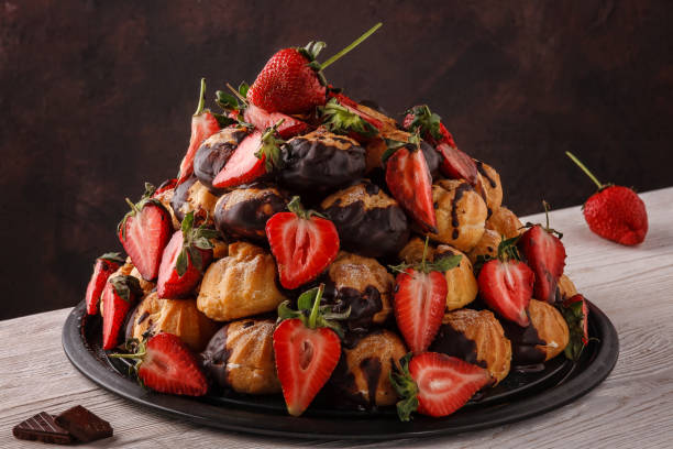 Cake made of eclairs and fresh strawberries drizzled with chocolate.