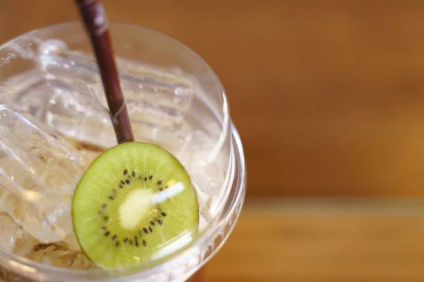Plastic cup of iced cold brew coffee with slice of kiwi fruit