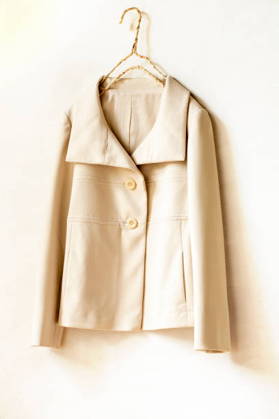 istock beige or white jacket hanging on clothes hanger on white background. 1241624695