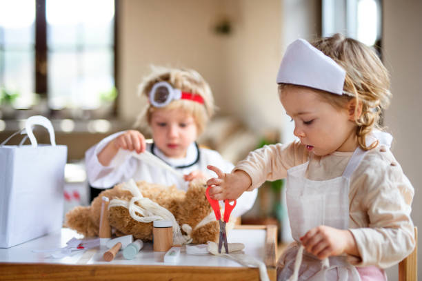 istock Two small children with doctor uniforms indoors at home, playing. 1241638145