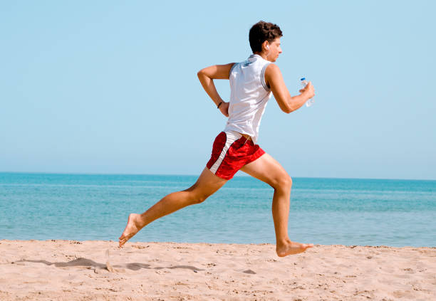 istock Young athletic man running on the beach 1241639626