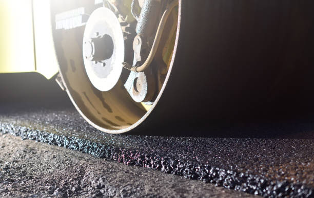Road repair, thin layer of new asphalt close-up and road roller stock photo