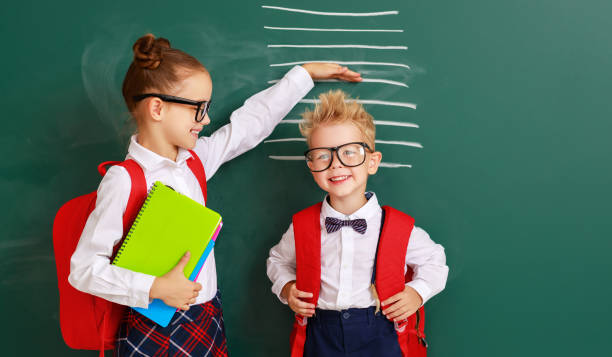 concetto di sviluppo nell'istruzione. bambini studenti ragazzo e ragazza misurare la crescita sulla lavagna della scuola - little boys measuring expressing positivity intelligence foto e immagini stock