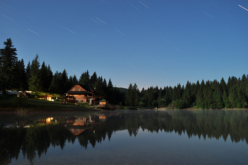 Forest and cottage reflecting in the lake at night