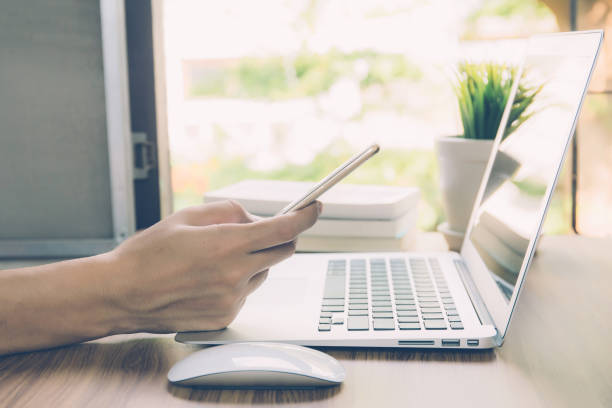 istock Hand of business man working from home using laptop computer to internet online on desk, lifestyle of new normal, social distancing, freelance work in stay home and look phone, communication concept. 1241670576