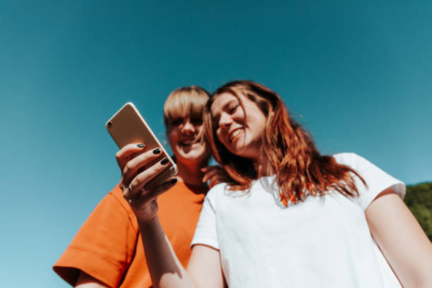 divertirse estudiantes chicas leyendo mensajes en el teléfono móvil - life lifestyles connection child fotografías e imágenes de stock