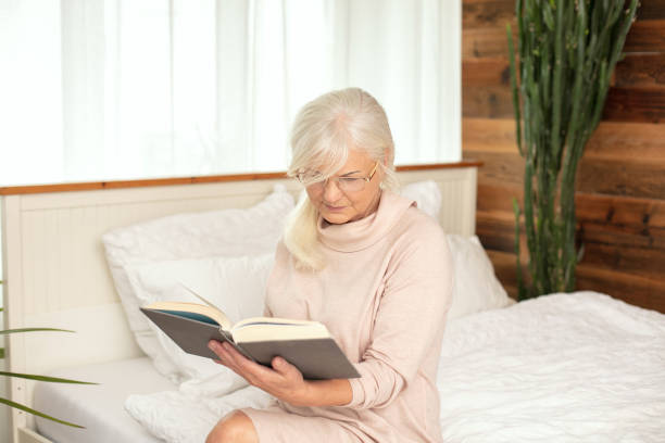 istock Senior woman reads, concentrated in a book. 1241689573