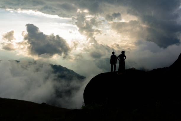 istock Silhouette manand woman standing on a rock. 1241697546