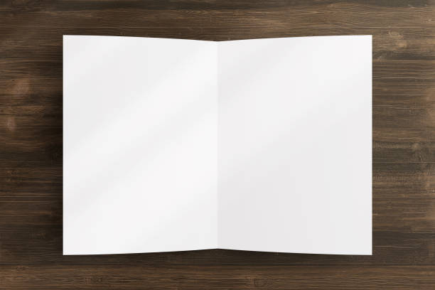 istock Blank opened bi-fold flyer brochure cover with soft overlay shadow on wooden background as template for design presentation, invitation card, etc. 1241699765