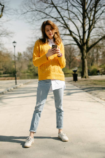 istock Young brunette girl using phone in a city park. 1241712506
