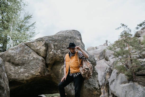 istock Hiker in an orange jacket with a backpack on top of a cliff 1241714011