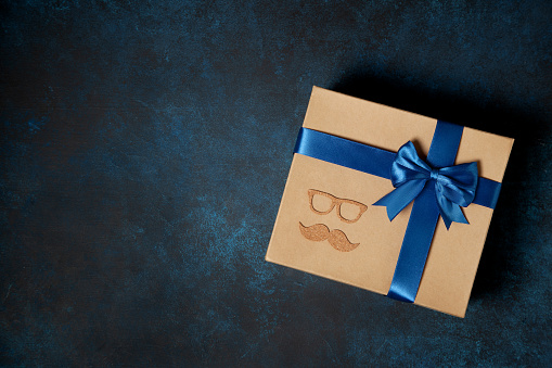 happy father's day gift concept. box with a blue ribbon on a blue background. view from above