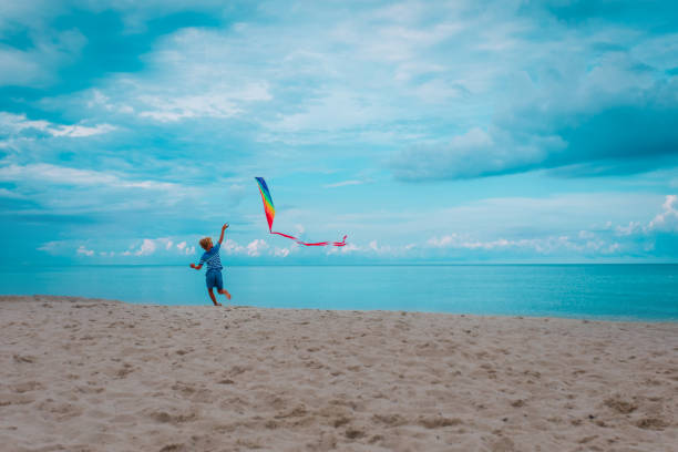 istock happy boy flying a kite on tropical beach 1241719226