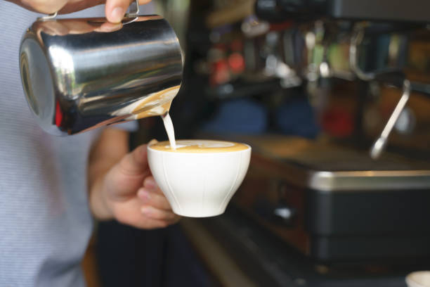 istock Hand pouring frothy steamed milk into coffee 1241721509