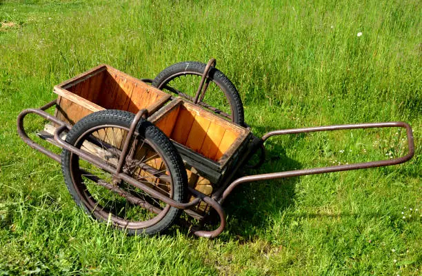 Photo of two-wheeled cart transport of hives to the apiary to facilitate beekeepers work in the collection of honey single axle wooden brown meadow metal construction