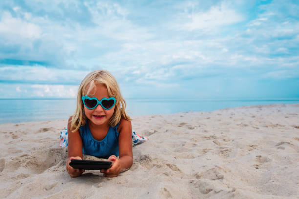 istock little girl reading e-book at sand beach, kid learning on vacation 1241725947