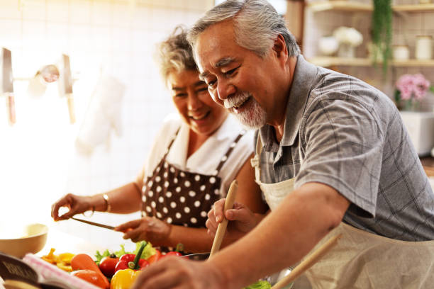 happiness senior elderly couple having fun in kitchen with healthy food for working from home. covid-19 - cooking senior adult healthy lifestyle couple imagens e fotografias de stock