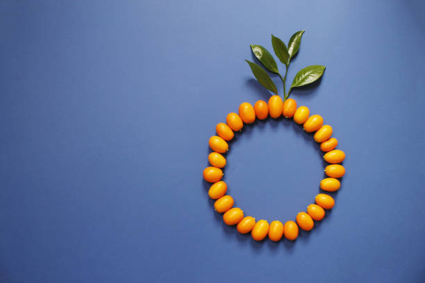 Circle formed for Kumquat and blue background. Top View. Mandarin chinese orange color, isolated of summer fruit.