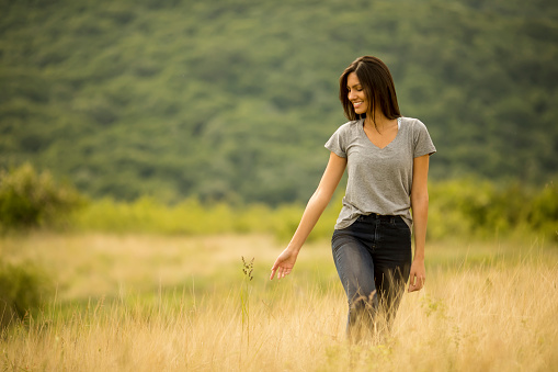 Pretty young woman walking in the field of tall grass