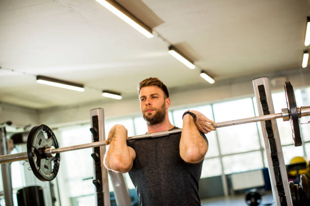 istock Young man working out with barbells in the gym 1241762510