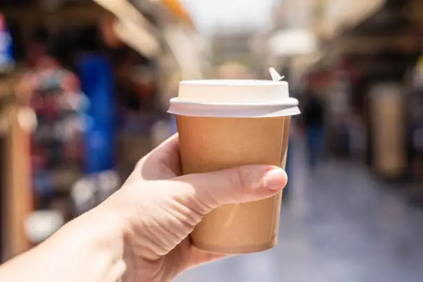 Girl with paper cup of coffee on a street. Coffee take away. Selective focus