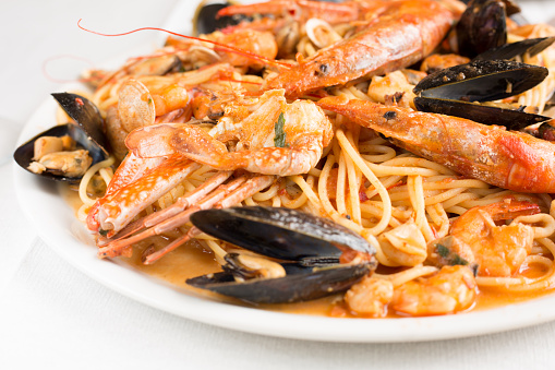 Spaghetti with seafood.Spicy spaghetti with mussels, clams, calamari, shrimp, crab, in tomato sauce close-up on a plate.Famous mediterranean Italian seafood dish -spaghetti allo scoglio