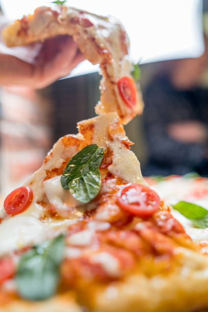 istock Slice pizza with tomatoes, mozzarella cheese and fresh green . Close up. 1241785035