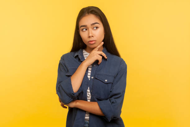 need to think it over. portrait of pensive girl in denim shirt touching chin while pondering idea, hesitating and having doubts - pensive question mark teenager adversity imagens e fotografias de stock