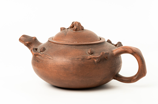 Brown clay teapot on white white background, studio shot.