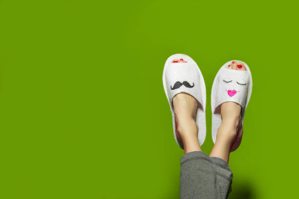 Couple in love Cute funny couple on green. Woman wearing pants lying with legs upwards wearing unusual slippers with faces of man and woman unusual couple stock pictures, royalty-free photos & images