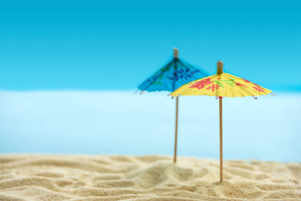 istock Sun umbrellas on sandy beach with blurry blue ocean and sky. Summer background. Soft focus 1241809910