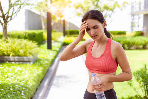 sport kobieta spragniony odwodniony w upalne dni odwodnienie, przegrzanie, pragnienie, udar cieplny, koncepcja opieki zdrowotnej z dziewczyną w silny słoneczny dzień. ona się zawroty głowy, omdlenia po uruchomieniu na zewnątrz w lecie - omdlenie zdjęcia i obrazy z banku zdjęć