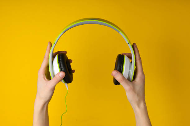 istock Hands hold stereo headphones on a yellow background. 1241845254