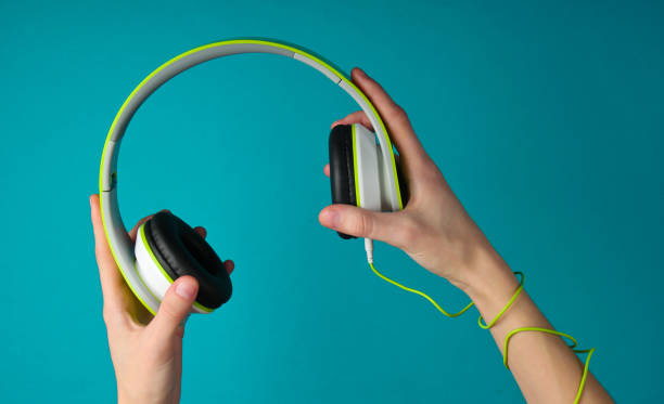 istock Hands wrapped in cable holding stereo headphones on blue background 1241846384